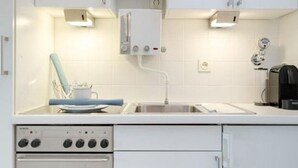 Ett modernt kök med vita skåp, en inbyggd ugn, en diskho och en diskmaskin.