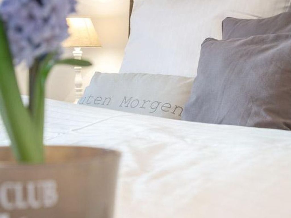 Un lit avec des oreillers, dont l’un porte l’inscription « Morgen » et l’autre affiche un visage flou.