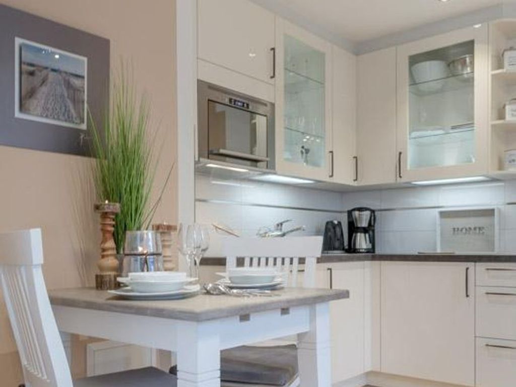 A modern kitchen with white cabinetry, a built-in oven, and a coffee maker.