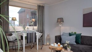 Un salon moderne comprenant un coin repas, un canapé gris, une table basse ronde et un lampadaire.