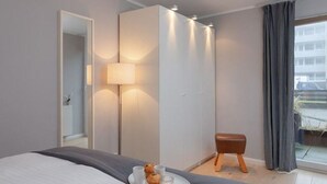 Une chambre d’hôtel moderne, équipée d’un lit, d’une table de chevet avec un plateau de petit-déjeuner, d’une lampe, d’une armoire et offrant une vue sur l’extérieur.