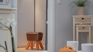 Une pièce moderne avec un tabouret en bois, une armoire blanche et une petite table sur laquelle est posée une plante.