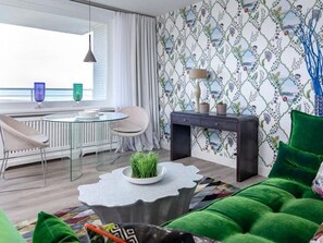 Un salon moderne avec un coin repas, une vue sur la mer et un papier peint à motifs.