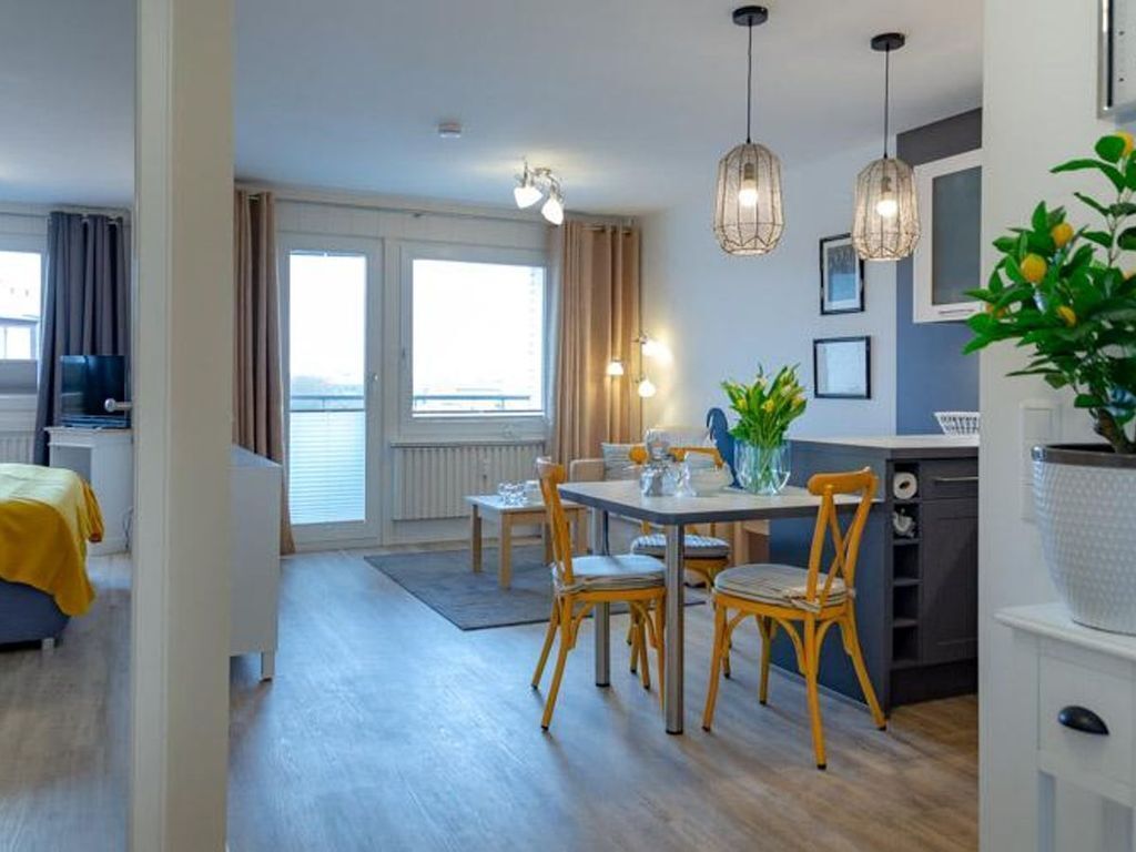 Een moderne hotelkamer met een zithoek, een keuken en een balkon met uitzicht.
