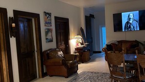 A spacious living room with a large TV, leather sofas, a wooden dining table, and a patterned rug. - Clean, New, Spacious, in Coconut Grove! (Miami)