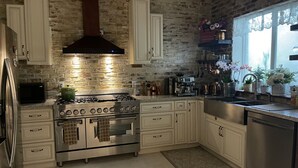 A kitchen with a brick wall, stainless steel appliances, and white cabinetry. - Clean, New, Spacious, in Coconut Grove! (Miami)