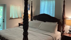 A four-poster bed with a wooden headboard, a ceiling fan, and a window with sheer curtains. - Clean, New, Spacious, in Coconut Grove! (Miami)