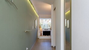 Ein schmaler Flur mit integriertem Sitzplatz, einem Fenster mit Blick ins Grüne und einer Tür mit Spiegel.