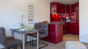 Una cocina moderna con armarios rojos y un comedor con una mesa dispuesta para dos.
