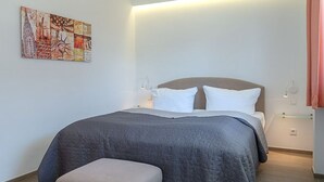 Ein Schlafzimmer mit einem Bett, Nachttischen, einer Bank und einem Wandbild.