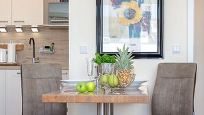 A modern kitchen with a dining table, two chairs, and a framed artwork on the wall. - Black Pearl - Elisabethstraße, Dünenburg House, modern 2-room apartment with (Sylt)