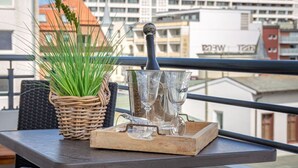 A balcony with a wicker plant, a tray with wine glasses, and a bottle. - Black Pearl - Elisabethstraße, Dünenburg House, modern 2-room apartment with (Sylt)