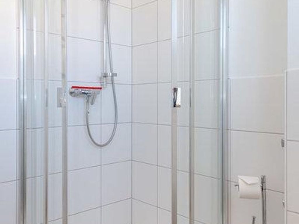 Eine moderne Duschkabine mit Glastüren, einer Handbrause und einem Handtuchhalter.