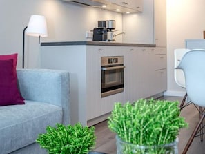A modern kitchen with a built-in oven, a coffee machine, and a dining area with a white chair.