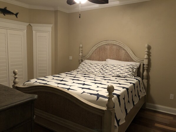 Una camera da letto con un letto, un comodino, una ventola a soffitto e un'ornamento a forma di pesce al muro.