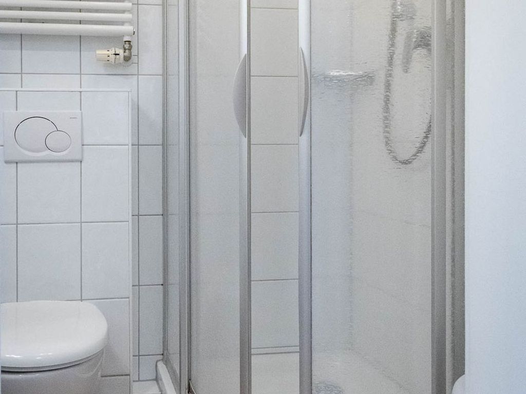 A bathroom with a toilet, a shower with a glass door, and a towel rack.