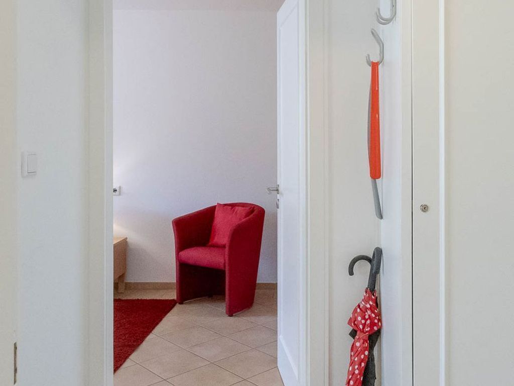 A doorway leading to a room with a red chair and a red rug.