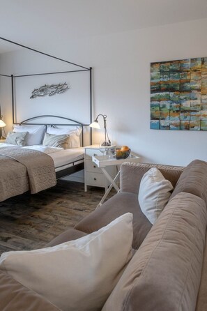 Un dormitorio con cama, mesita de noche, lámpara y un cuadro en la pared.