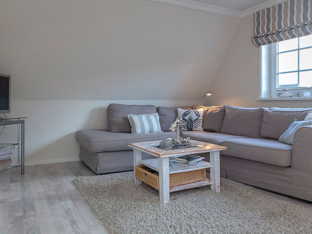 A living room with a grey sofa, a small coffee table, and a TV on a stand.