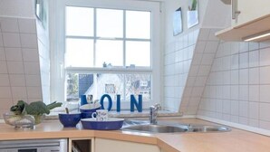 A modern kitchen with a window, a dishwasher, and a sink. - House Senwai - Surfside 2 - Top modern 3 room apartment SURFSIDE 1 in quiet, (Sylt)