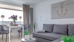 Una sala moderna con un sofá gris, una mesa de centro redonda y un comedor con dos sillas y una mesa.