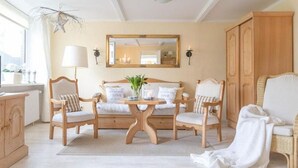A hotel room with a wooden bed, two chairs, a small table, a mirror, and a wardrobe.