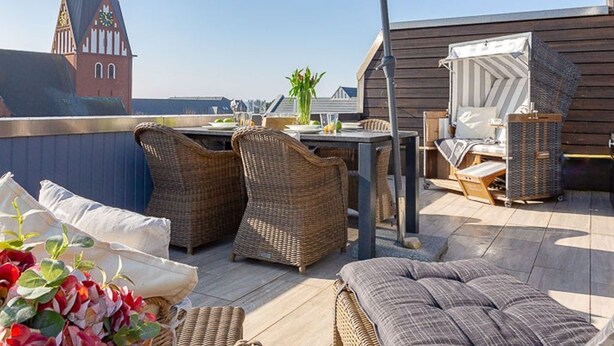 An outdoor patio with wicker furniture, a table, and an umbrella. - Big Wave - BIG WAVE maisonette, central, 2 bedrooms, swimming pool, roof terrace, (Sylt)