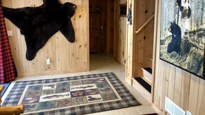 Un intérieur en bois orné d’une tête d’ours fixée au mur, d’un tapis à motifs et d’un tableau représentant un ours dans une forêt.