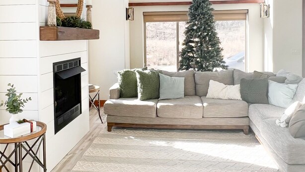 Una sala moderna con chimenea, un ventanal amplio, un árbol de Navidad y una zona de estar acogedora.