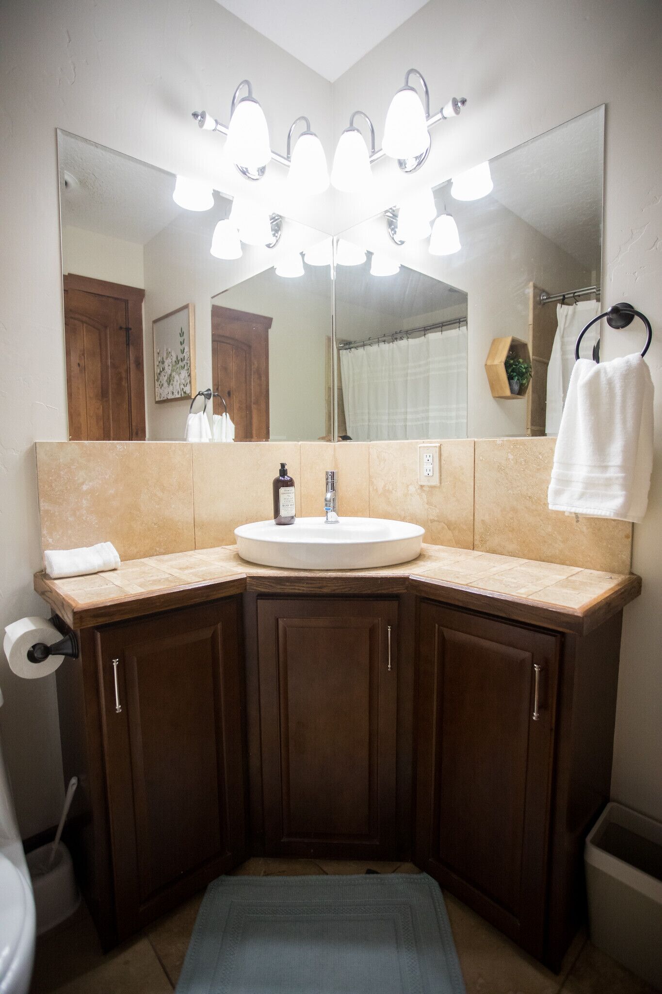 A bathroom with a large mirror, a sink, and a vanity with cabinets.