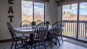 Un comedor con una mesa redonda, seis sillas y vistas al exterior a través de grandes puertas correderas de vidrio.