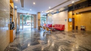 A modern lobby with a marble floor, a red sofa, and a reception desk.