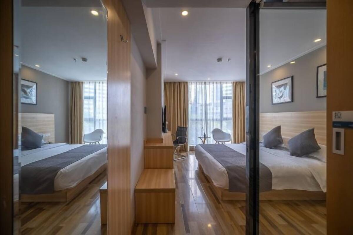 A hotel room with two beds, a desk, and a chair.