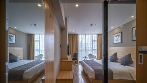 A hotel room with two beds, a desk, and a chair.