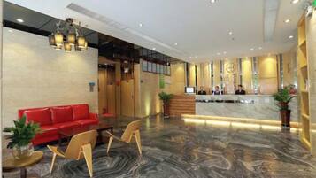 Un vestíbulo de hotel con mostrador de recepción, un sofá rojo y piso de mármol.