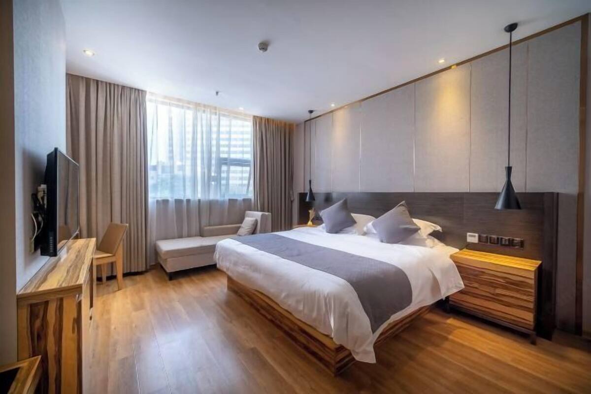 A modern hotel room with a large bed, a desk, and a TV.