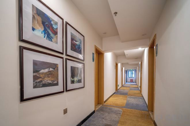 A hallway with framed pictures on the walls, a carpeted floor, and doors leading to other rooms.