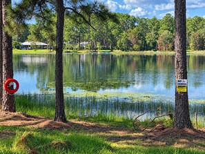 A tranquil lake with a no swimming sign, surrounded by trees and a distant building.