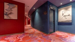 Een hotelgang met een rode muur, een blauwe muur en een kamerbreed tapijt met een patroon.