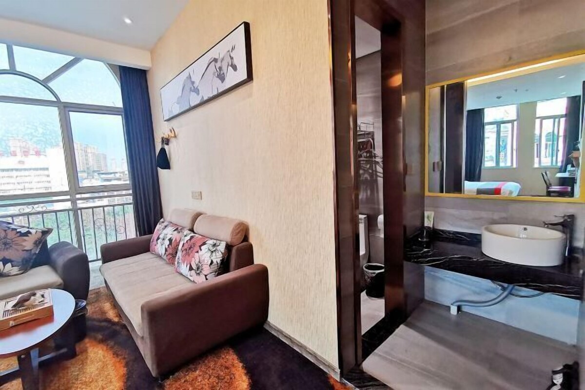 Un moderno salón con sofá, una mesa de centro y un amplio ventanal con vistas a la ciudad.
