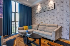 A living room with a sectional sofa, a coffee table, and a patterned wallpaper. - Roman Hotel (Jian'ou)