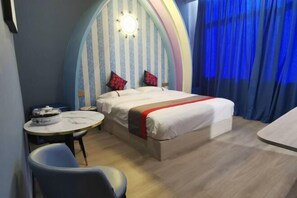 A hotel room with a bed, a round table, and a chair.