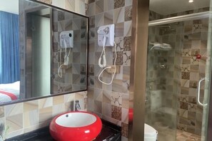 Un baño con un lavabo rojo, un espejo grande y dos secadores de pelo montados en la pared.