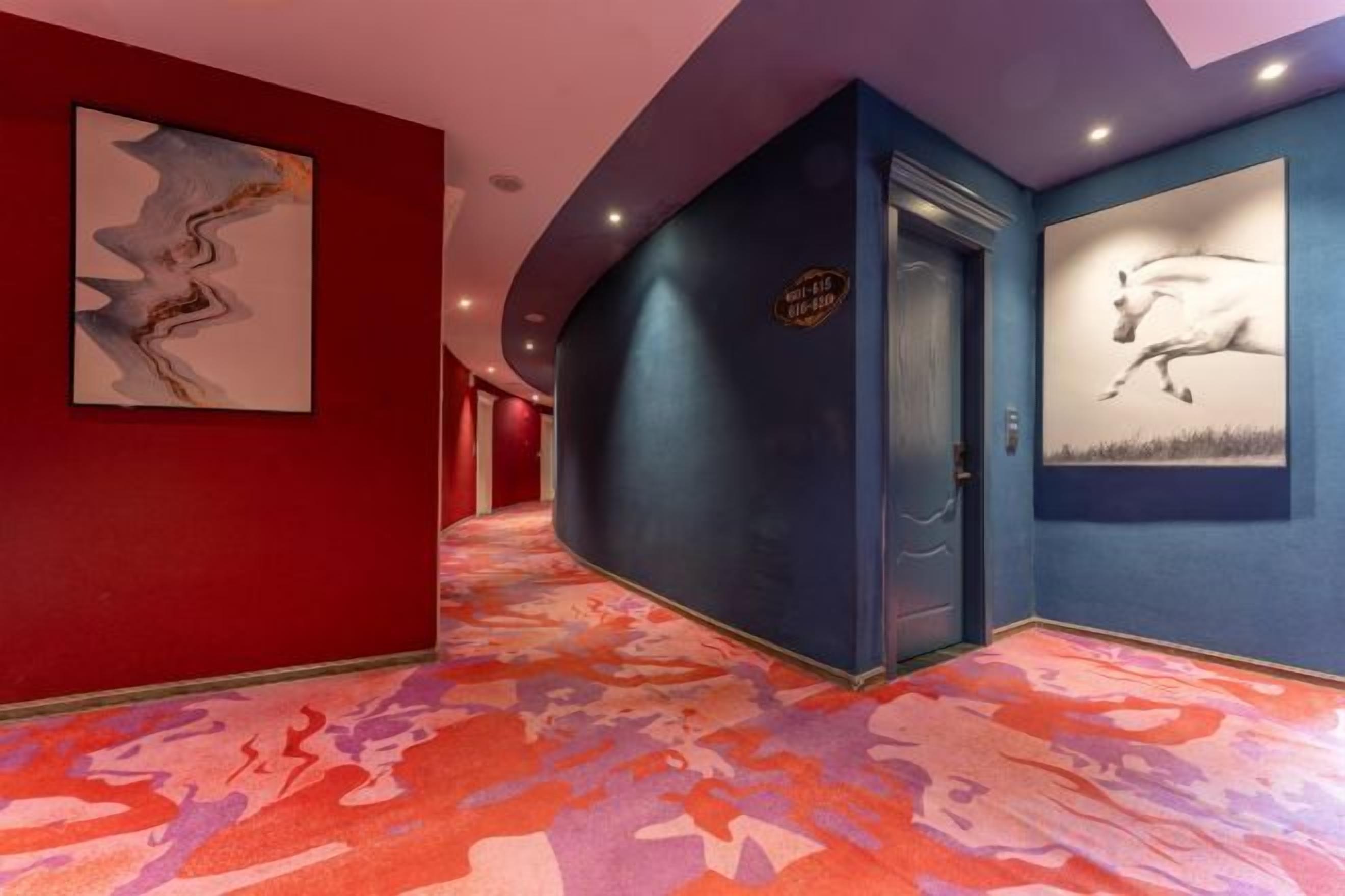 Un pasillo de hotel con una pared roja, una pared azul y una alfombra colorida.