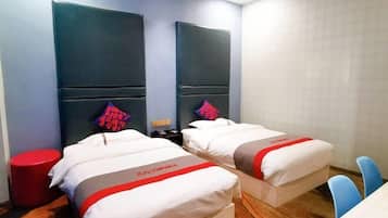 A hotel room with two beds, a red stool, and a table with chairs.