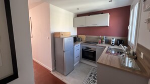 Eine kleine Küche mit Kühlschrank, Backofen, Spüle und einer Holz Arbeitsplatte.