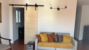 Ein Wohnzimmer mit grauem Sofa, einer Holztür zum Schieben und einer schwarzen Wandleuchte.