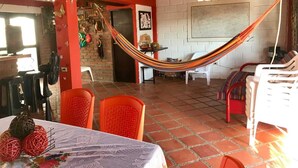 A spacious room with a hammock, red chairs, a table with decorative balls, and a brick wall. - cabaña a 10 minutos de la playa, taganga , colombia (Santa Marta)