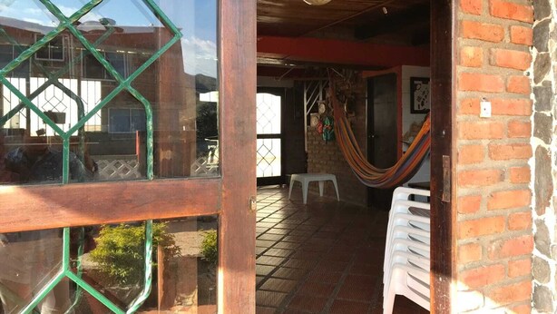 An open doorway leading to a room with a brick wall, a hammock, and a white plastic chair. - cabaña a 10 minutos de la playa, taganga , colombia (Santa Marta)