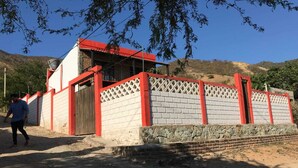 A building with a red roof and white walls, surrounded by a red and white fence. - cabaña a 10 minutos de la playa, taganga , colombia (Santa Marta)